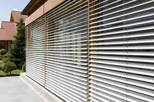 Three facade blinds with semi-open slats mounted modularly, shielding a large patio window